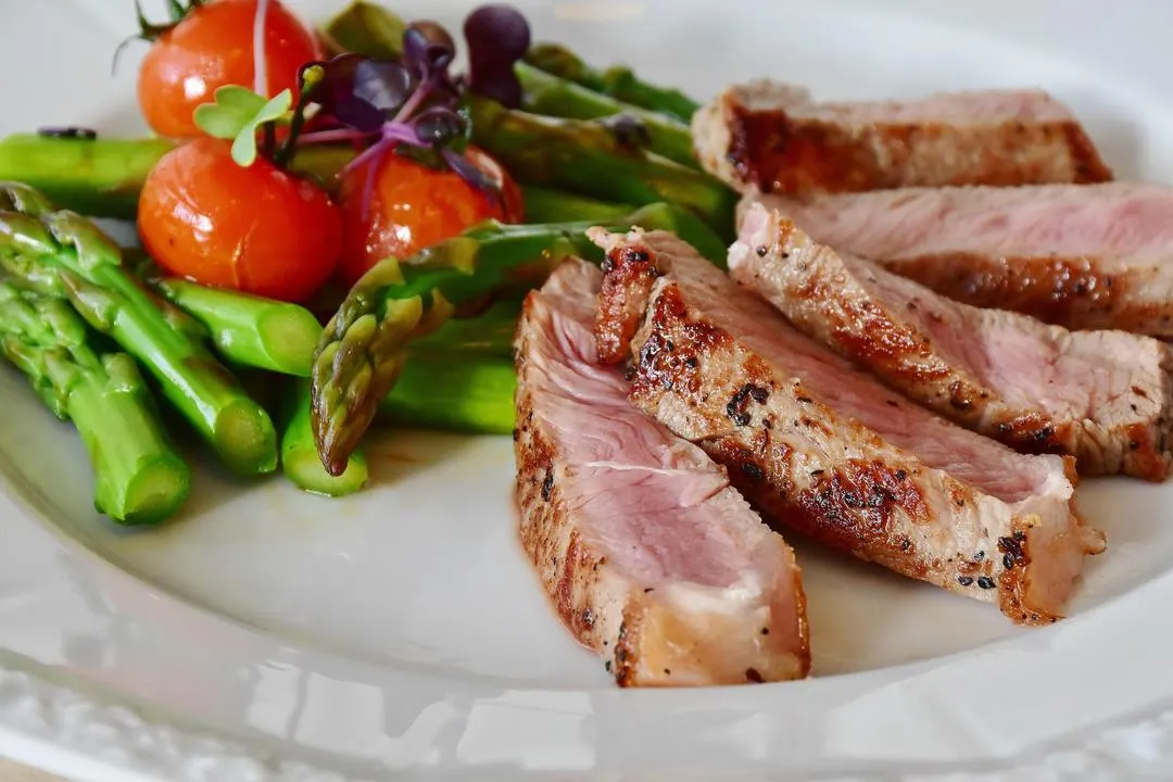 Assiette de viande grillée avec asperges vertes et tomates cerises servie au restaurant Les Feuillardiers