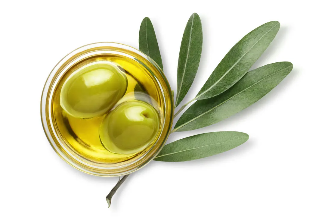 Bol d'huile d'olive avec olives vertes et branche d'olivier