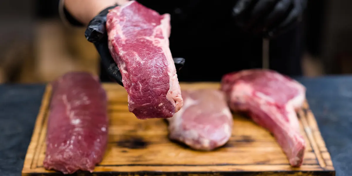 Illustration La Fraîcheur : boucher ganté présentant des morceaux de viande sur planche à découper