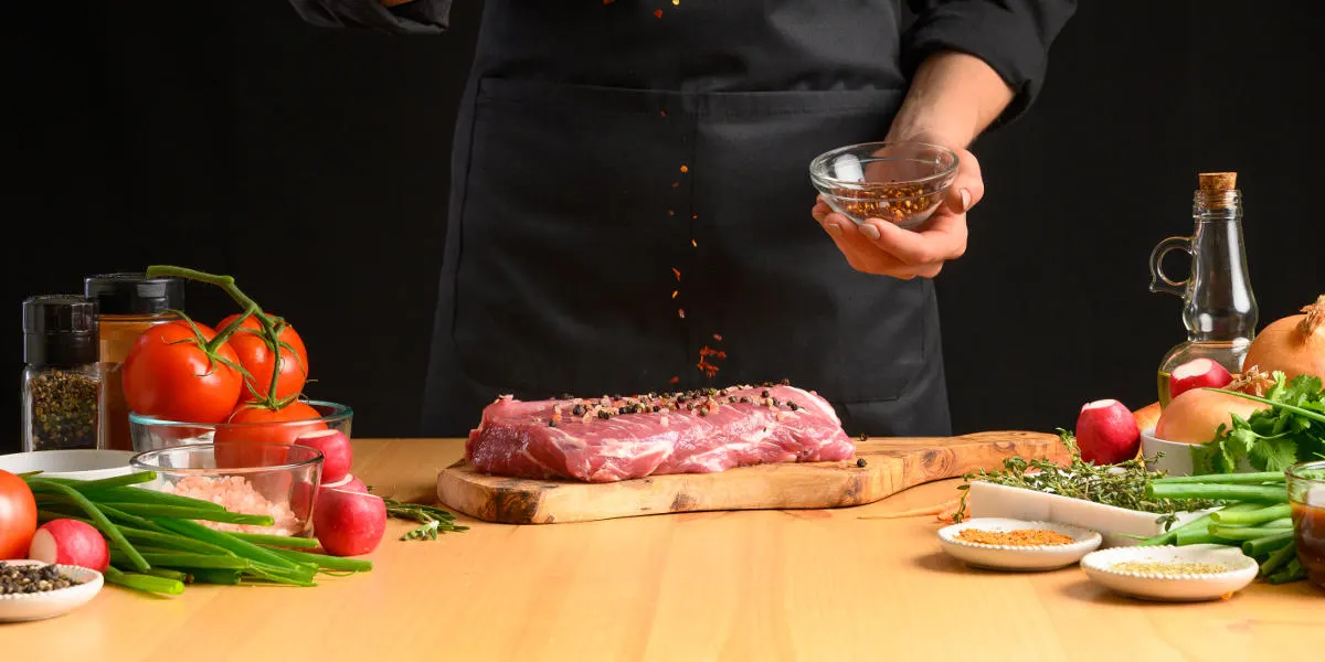 Illustration La Gastronomie : boucher saupoudrant des épices sur une pièce de viande entourée de légumes