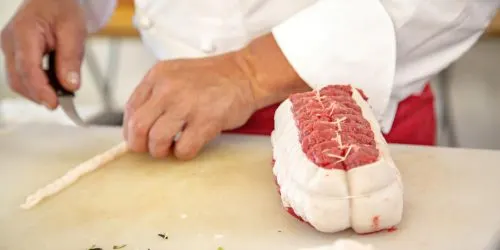 Boucher préparant une pièce de viande sur sa planche à découper