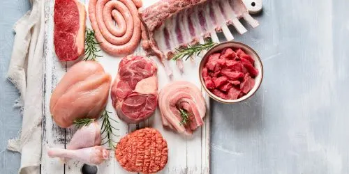 Sélection de viandes rouges et blanches disposées sur une planche en bois