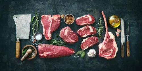 Morceaux de viande sélectionnés avec herbes, épices et couteau sur fond sombre