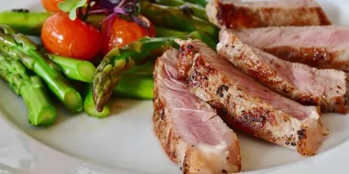 Assiette de viande grillée servie avec asperges vertes et tomates cerises