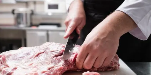 Boucher désossant une pièce de viande sur sa planche dans l'atelier